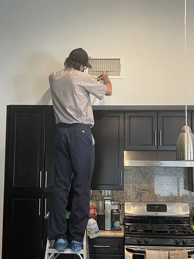Technician inspecting an air vent during HVAC service in Burnet